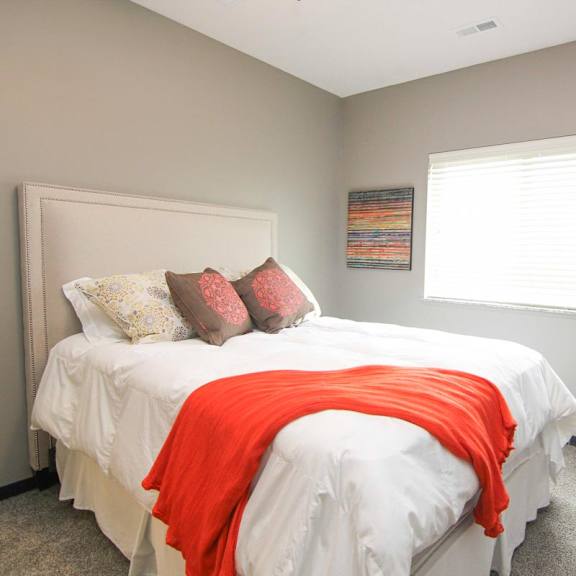 A bedroom with a bed, chair, and window.