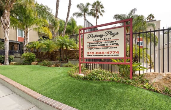 a sign in front of a yard with grass and palm trees
