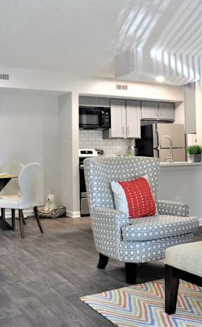 A living room with a grey couch, a white coffee table, and a dining table with chairs.