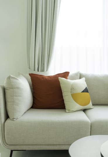 a living room with white walls and a grey sofa with colourful cushions