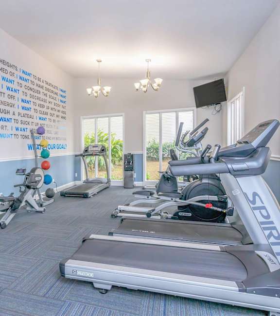 A gym with a wall of inspirational quotes and exercise equipment.