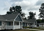 Thumbnail 6 of 36 - a white and gray house with a porch and a lawn