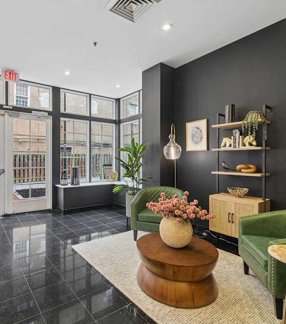 A black and white living room with a large window and a green chair.