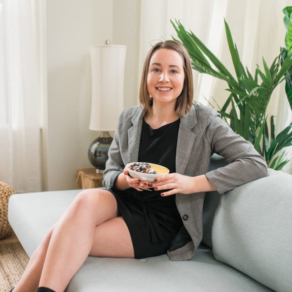 a woman sitting on a couch holding a bowl of food