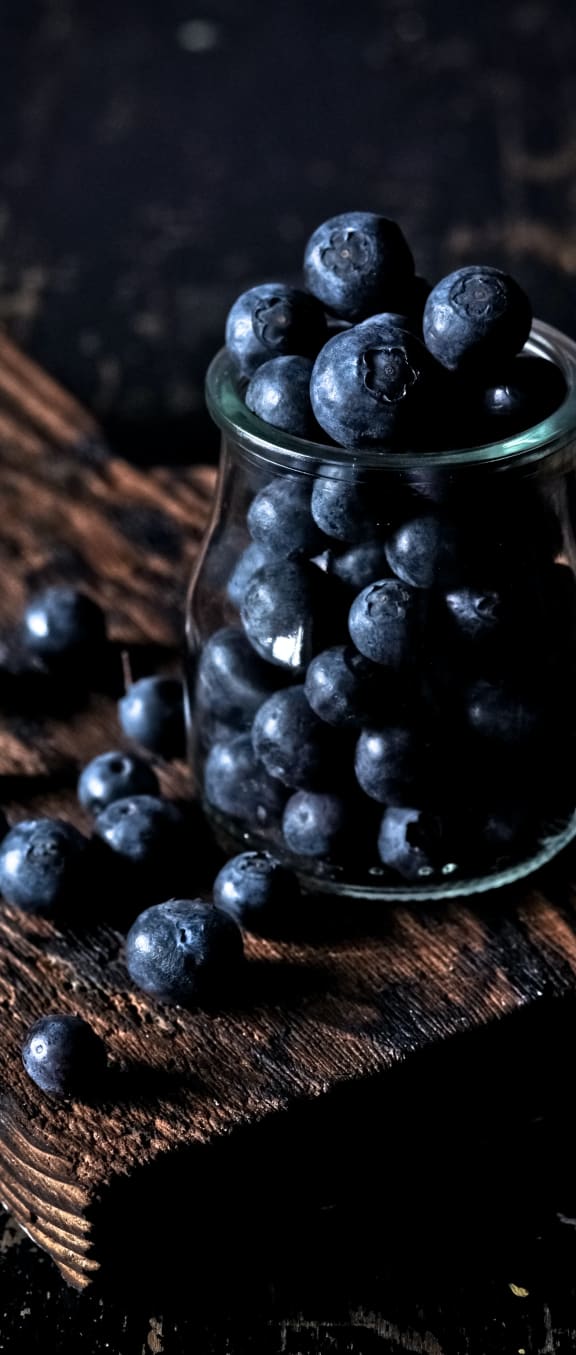 a jar of blueberries on a wooden table