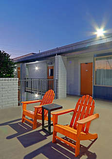Two orange chairs and a table are on a patio.