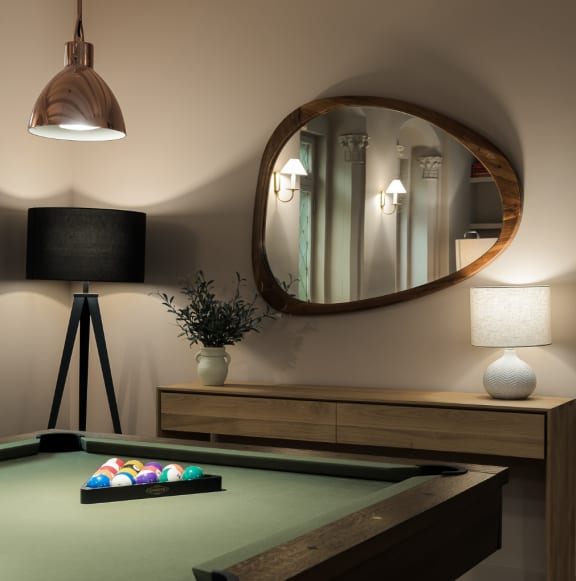 a pool table in a room with a mirror and a lamp