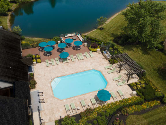 Sundeck and resort-style pool with lounge chairs, umbrellas, patio tables, and BBQ area at The Coleman in Canal Winchester