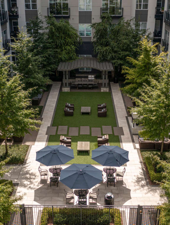 an aerial view of a courtyard with a grassy area and umbrellas