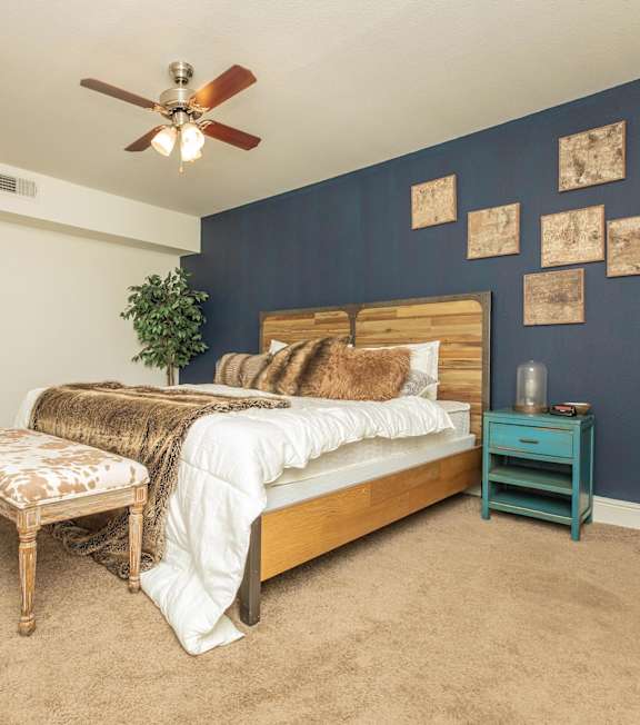 A bedroom with a bed, a chair, and a potted plant. at The Cove at State Street Apartments, Baton Rouge, LA, 70802