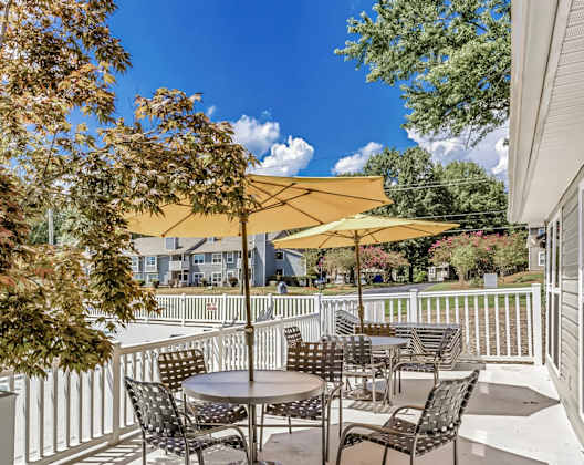 A patio with a table and chairs is surrounded by a white fence.