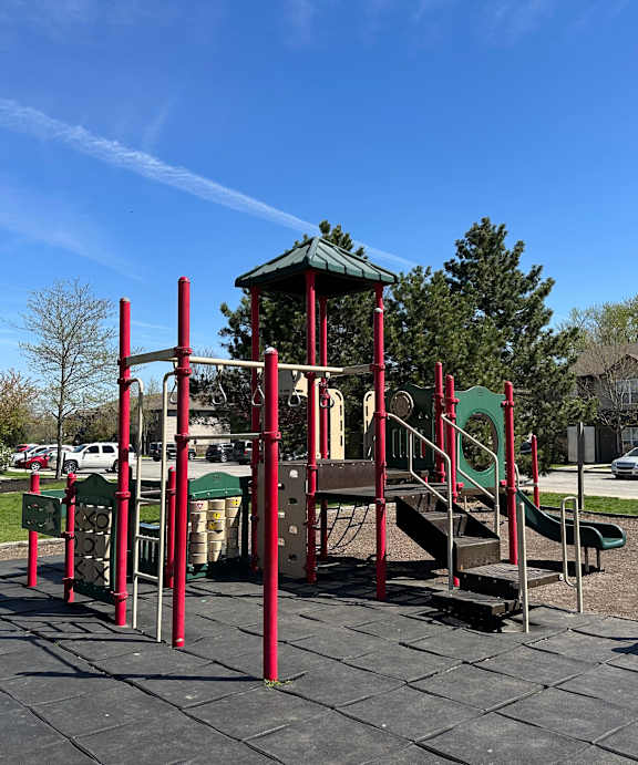 A playground with a red and green slide and a green canopy. at Northampton Village Apartments, Indianapolis, Indiana