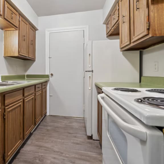 A kitchen with wooden cabinets and a white stove top oven.