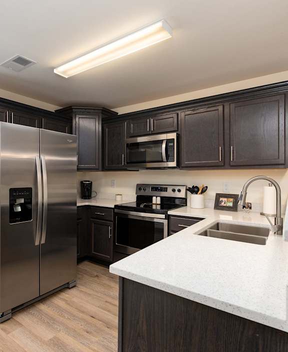 A kitchen with a stainless steel refrigerator and black cabinets.