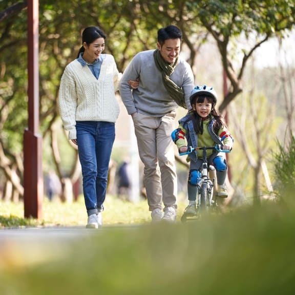 two parents and their child going for a walk in a nearby park