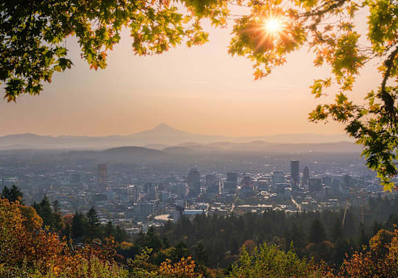 Portland, Oregon, cityscape at dusk with a mountain in the distance is bathed in sunlight