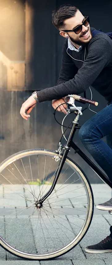 A man is riding a bicycle on a sidewalk.