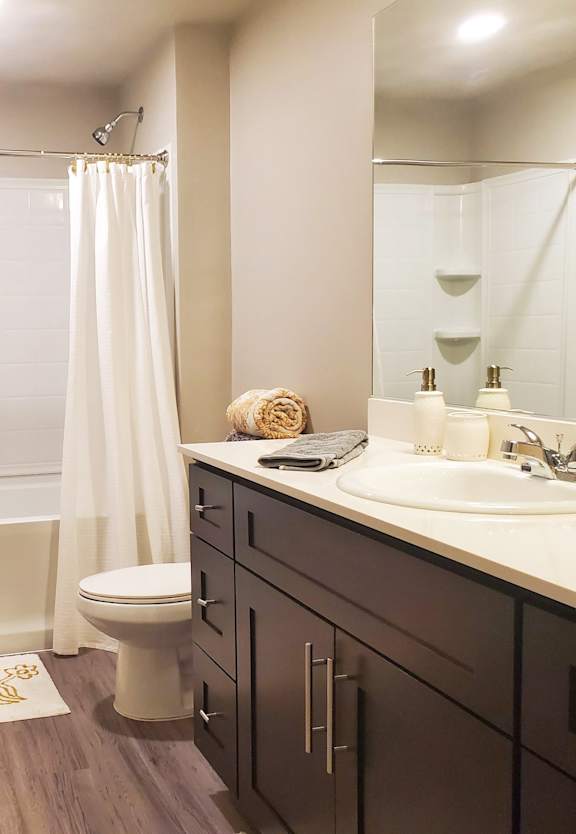 A bathroom with a white tub and sink, a white toilet, and a white shower curtain.