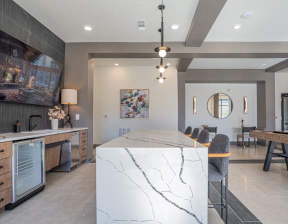 A modern kitchen with a marble island and a large painting on the wall.