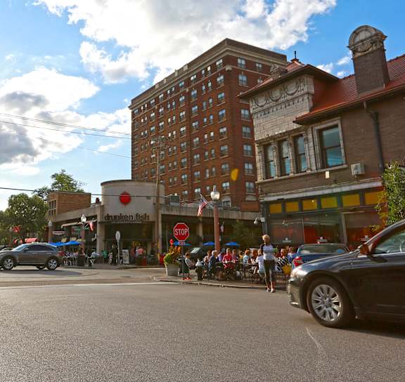 A sunny day in a town square with cars and buildings.