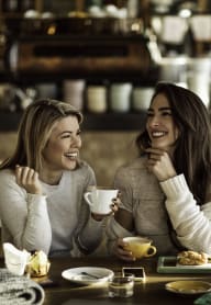 Two ladies at a coffee shop enjoying a treat together while laughing. at Pinecrest Apartments, Davis, California