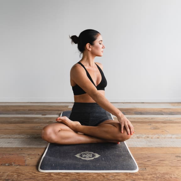 woman Seated on Yoga Mat with Head Turned Mid Stretch