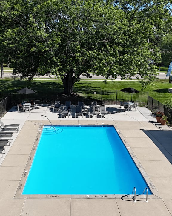 a swimming pool with chaise lounge chairs and trees in the background