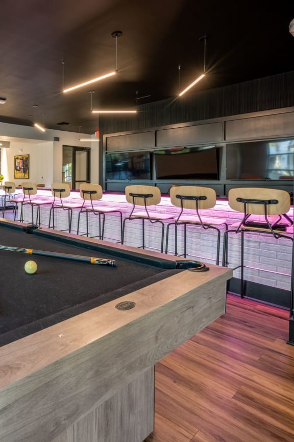 a pool table in a room with tables and chairs at 19 South Apartments in Kissimmee, FL