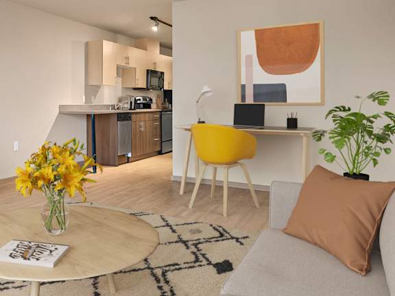 A living room with a grey couch, a coffee table, a yellow chair, a TV, and a potted plant.