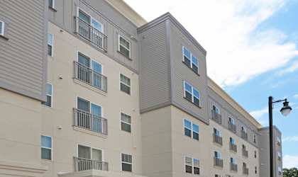 A modern apartment building with a parking lot in front at Arbours at Tumblin Creek ~ Active 55+ Adult Community, 32608