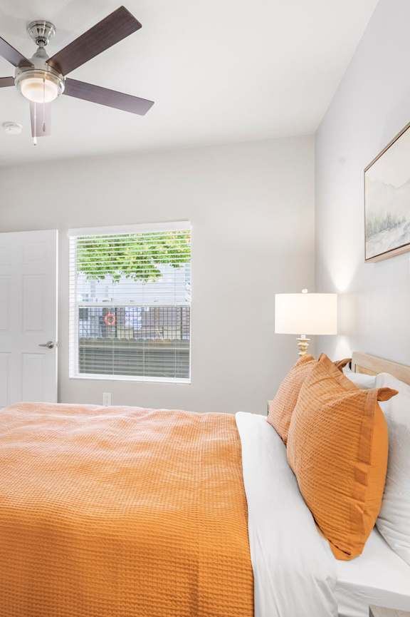 A bedroom with a bed covered in an orange blanket and a painting of a bull on the wall.