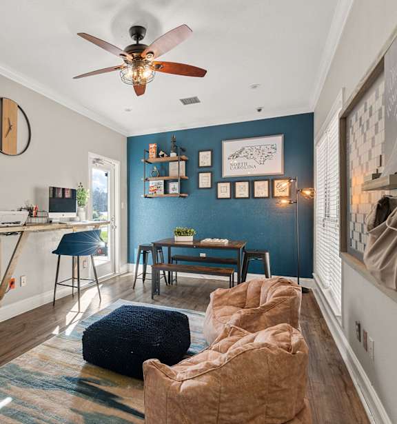 a living room with a couch and a desk and a ceiling fan