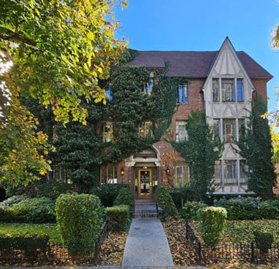 the front of a house with a garden and a sidewalk