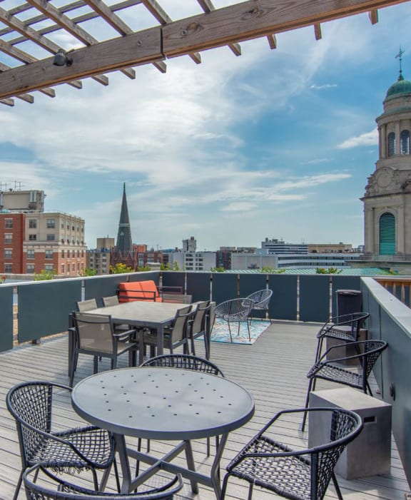 a rooftop patio with tables and chairs and a building in the background