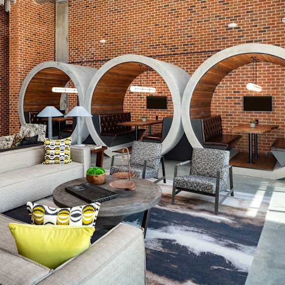 a living room with couches and chairs and a large brick wall