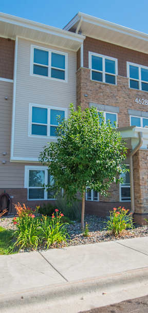 A modern two-story apartment building with a car parked in front.