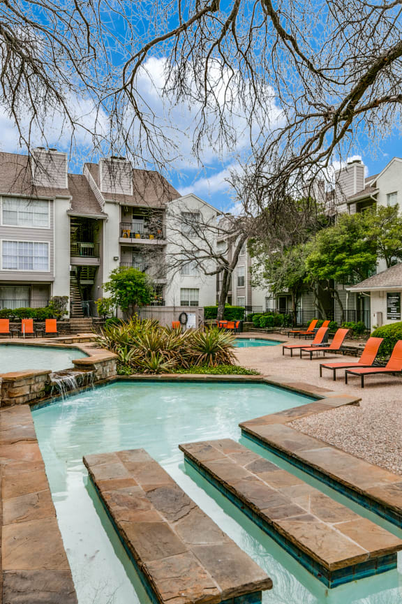a swimming pool with orange chairs and a building in the background