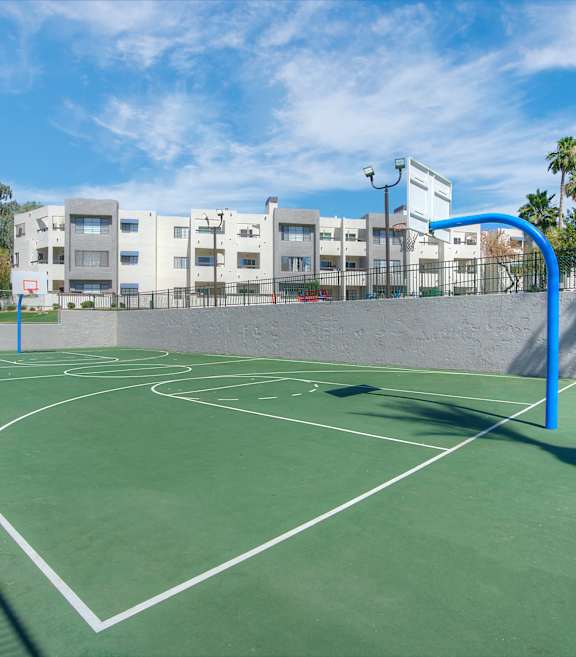 a green basketball court with buildings in the background at Vaseo Apartments, Phoenix, Arizona