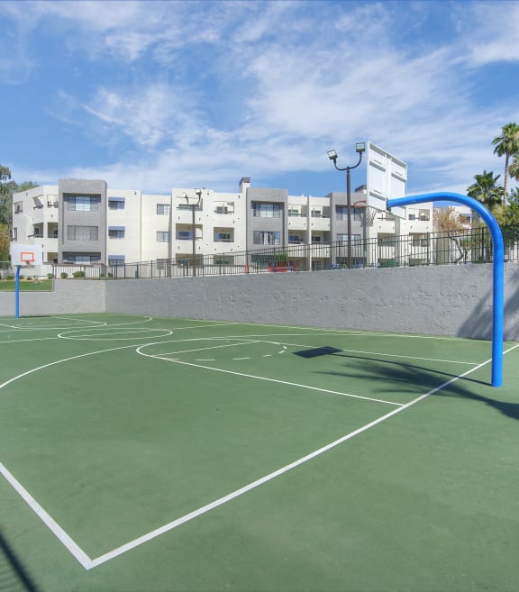 a green basketball court with buildings in the background