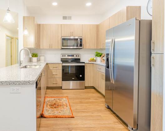A modern kitchen with a refrigerator, microwave, and oven.
