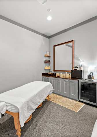 A room with a massage table and a mirror on the wall.