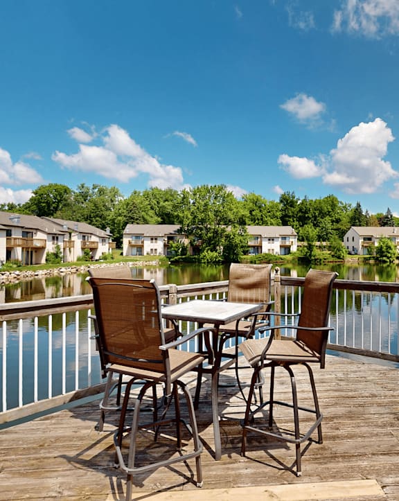 A table with chairs is on a deck overlooking a body of water.