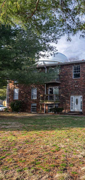 A brick apartment building with a green lawn in front.
