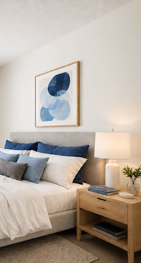 A bedroom with a bed, nightstand, and two framed pictures on the wall.