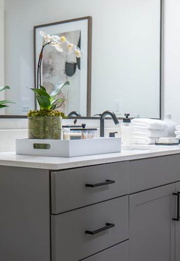A bathroom with a large mirror, a sink, and a towel hanging on the door.