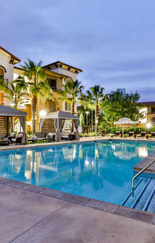 a swimming pool with chairs and umbrellas at night at Capriana at Chino Hills, Chino Hills, CA, 91709