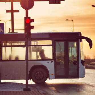 a bus stopped at a traffic light with the sun setting in the background