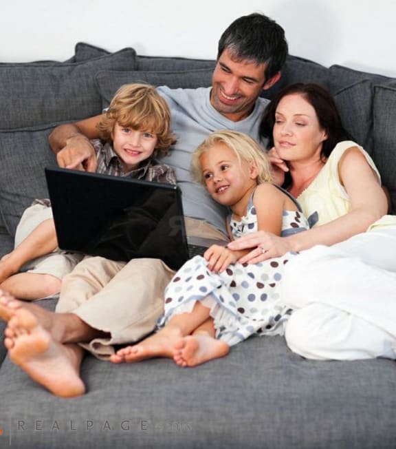 a family sitting on a couch looking at a laptop