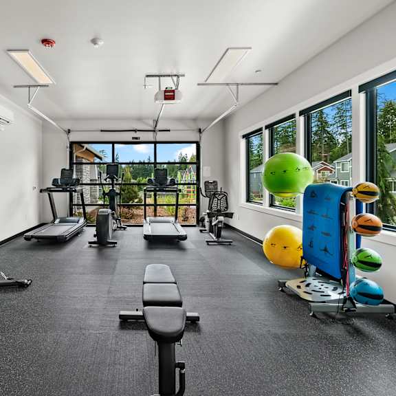 A gym with a variety of equipment including a treadmill, weights, and exercise balls.