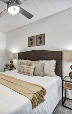 A bedroom with a bed, nightstand, and a painting on the wall.